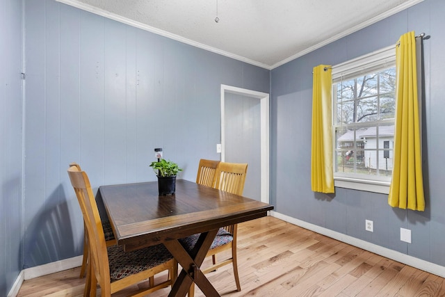 dining area featuring light wood-type flooring and crown molding