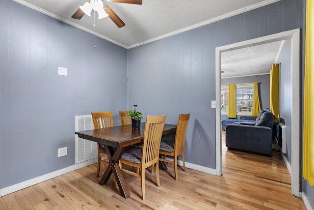 dining room with a textured ceiling, light hardwood / wood-style floors, ceiling fan, and crown molding