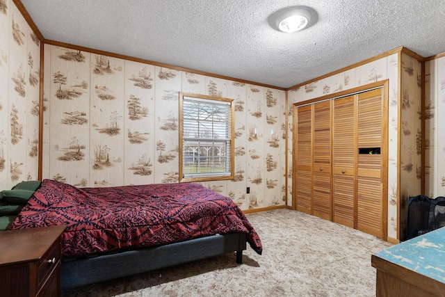 carpeted bedroom featuring a closet, a textured ceiling, and ornamental molding