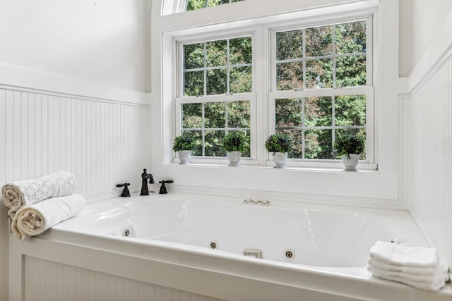 bathroom featuring plenty of natural light and a tub to relax in