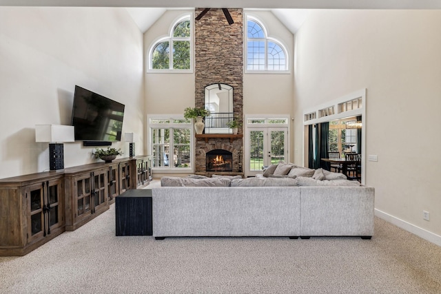 carpeted living room featuring french doors, high vaulted ceiling, ceiling fan, and a stone fireplace