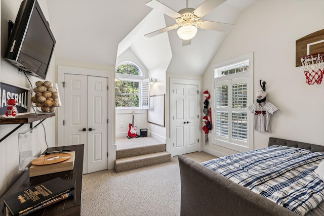 carpeted bedroom featuring ceiling fan, lofted ceiling, and two closets