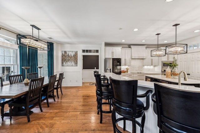 kitchen with stainless steel appliances, light hardwood / wood-style flooring, pendant lighting, a kitchen bar, and white cabinets