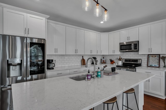 kitchen featuring white cabinets, light stone countertops, stainless steel appliances, and hanging light fixtures