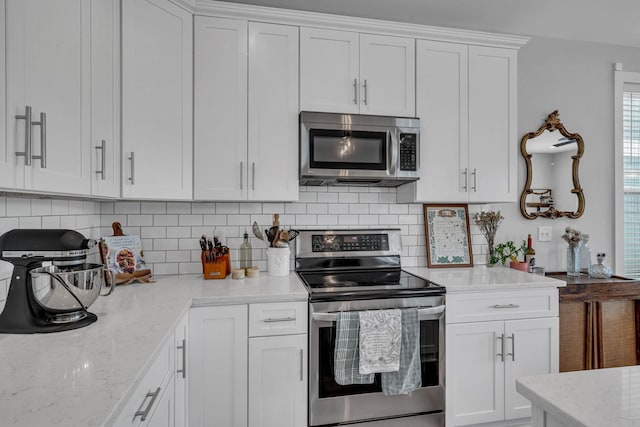 kitchen featuring decorative backsplash, light stone counters, white cabinetry, and appliances with stainless steel finishes