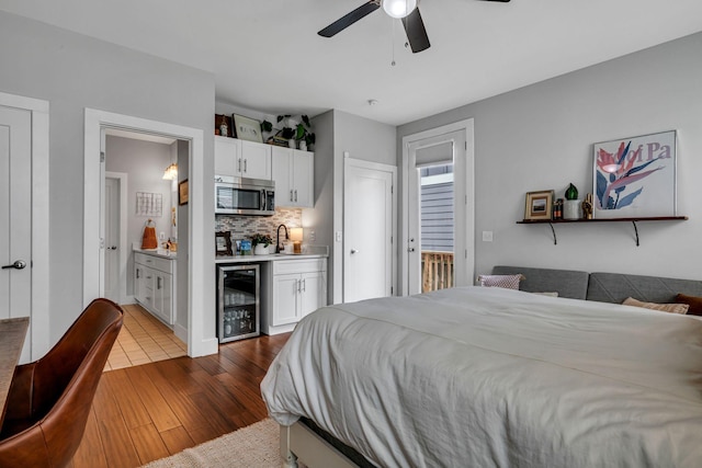 bedroom featuring connected bathroom, ceiling fan, sink, beverage cooler, and hardwood / wood-style flooring