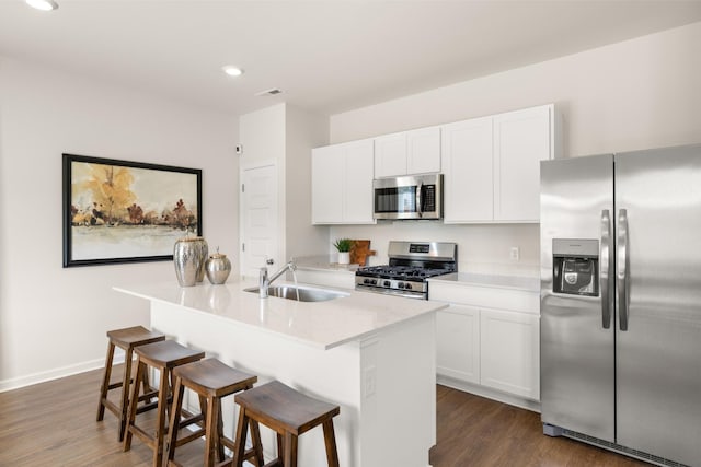 kitchen featuring appliances with stainless steel finishes, a kitchen island with sink, dark wood-type flooring, sink, and white cabinets