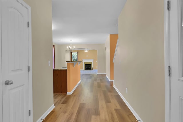 corridor with a notable chandelier and light hardwood / wood-style floors