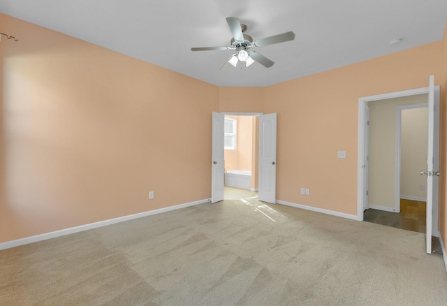 unfurnished bedroom with ceiling fan, ensuite bathroom, and light colored carpet