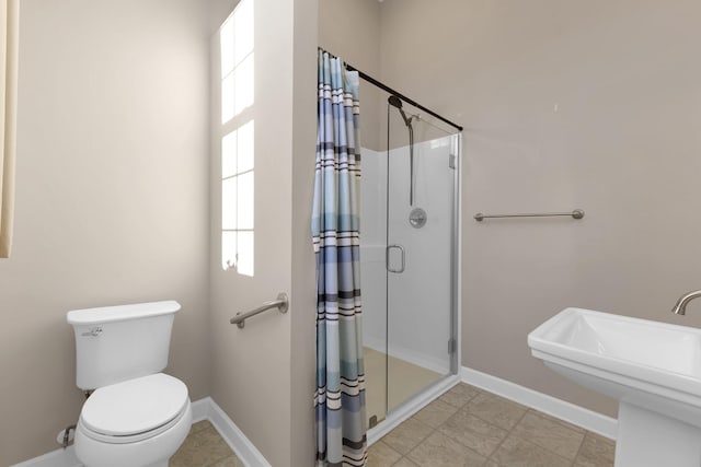 bathroom with toilet, a shower with shower door, and sink