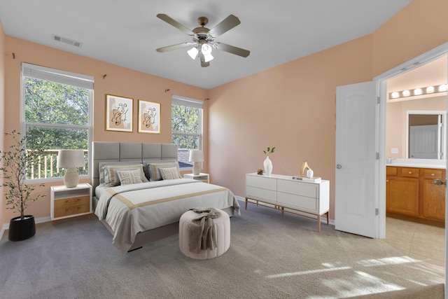 carpeted bedroom featuring multiple windows, connected bathroom, and ceiling fan