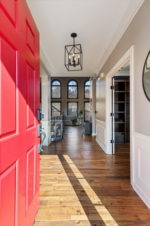 foyer featuring an inviting chandelier, crown molding, and hardwood / wood-style flooring