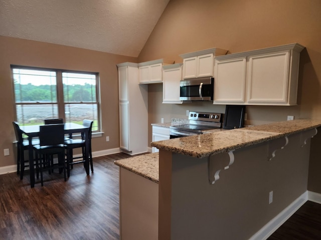 kitchen with a kitchen breakfast bar, kitchen peninsula, white cabinets, and stainless steel appliances