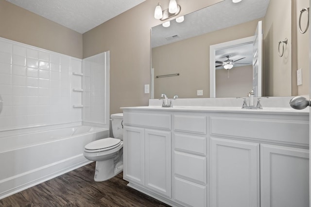 full bathroom with a textured ceiling, hardwood / wood-style floors, bathing tub / shower combination, vanity, and toilet