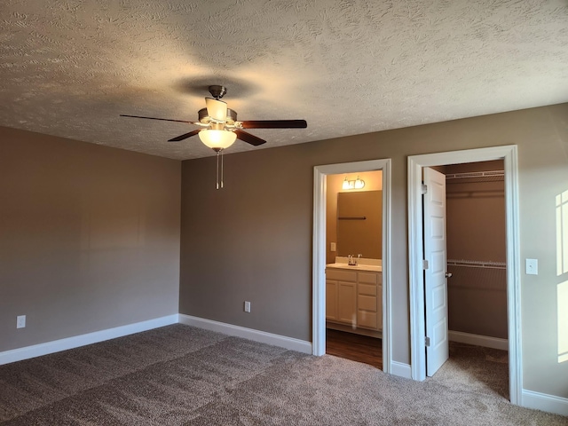 unfurnished bedroom featuring a walk in closet, ceiling fan, connected bathroom, a closet, and carpet flooring