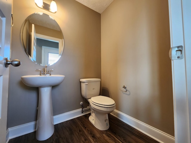 bathroom featuring wood-type flooring, sink, a textured ceiling, and toilet