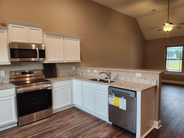 kitchen with lofted ceiling, kitchen peninsula, sink, appliances with stainless steel finishes, and white cabinets