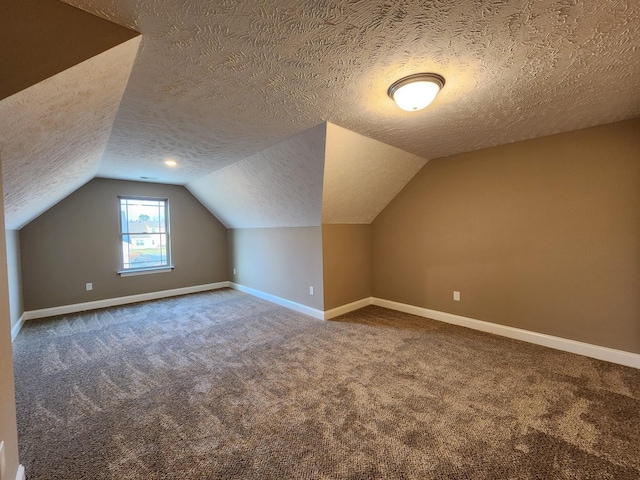 additional living space with a textured ceiling, lofted ceiling, and carpet