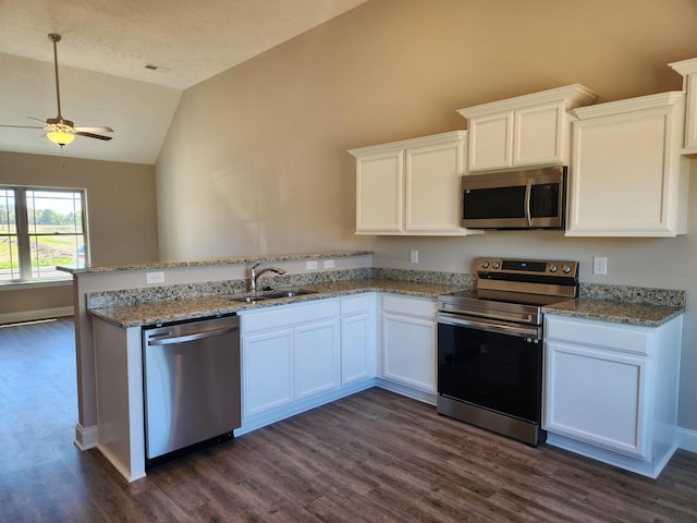 kitchen featuring lofted ceiling, sink, appliances with stainless steel finishes, white cabinets, and light stone counters