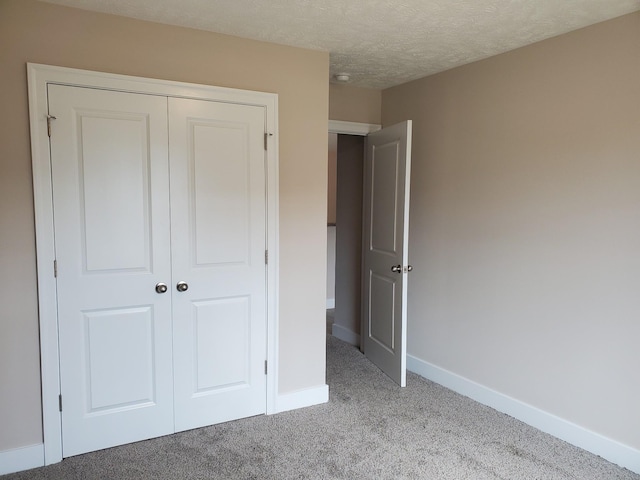 unfurnished bedroom with a textured ceiling, a closet, and light colored carpet