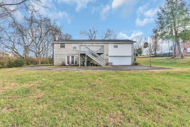 back of house featuring a yard, a deck, and a garage