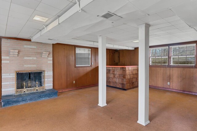 basement featuring wood walls, a fireplace, and electric panel