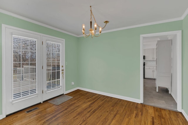 empty room featuring hardwood / wood-style flooring, ornamental molding, and a chandelier