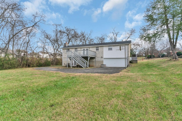 back of house featuring a lawn, a garage, and a deck