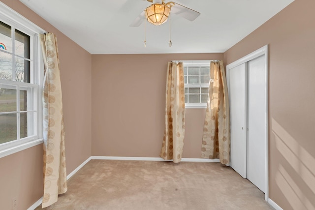 unfurnished bedroom with multiple windows, ceiling fan, a closet, and light carpet