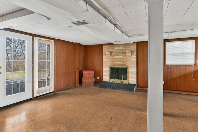 unfurnished living room with a brick fireplace and wooden walls