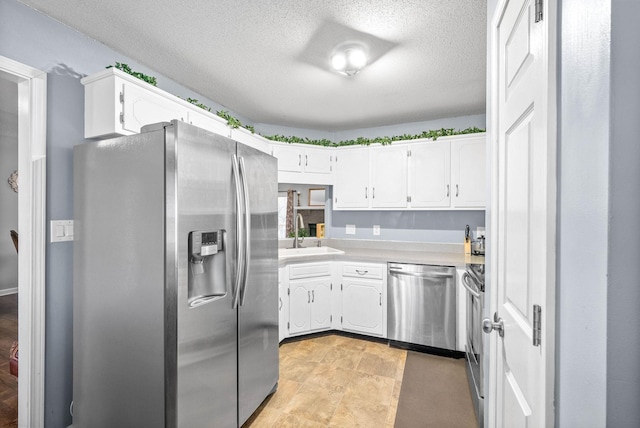 kitchen featuring a textured ceiling, white cabinetry, sink, and appliances with stainless steel finishes