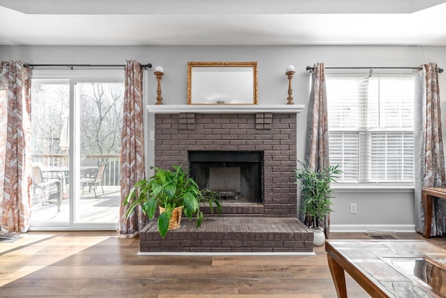 living room featuring hardwood / wood-style floors, a wealth of natural light, and a brick fireplace