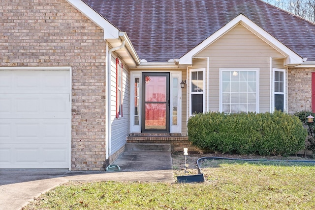 view of exterior entry featuring a lawn and a garage