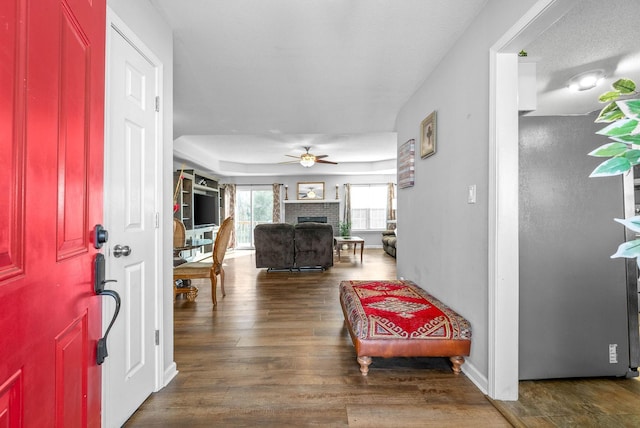 entrance foyer with a textured ceiling, ceiling fan, dark hardwood / wood-style floors, and a brick fireplace