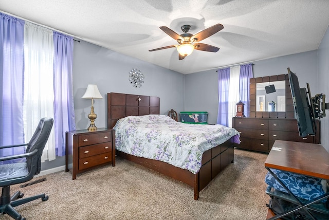 bedroom featuring ceiling fan, light carpet, and a textured ceiling