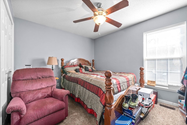 carpeted bedroom with ceiling fan, a closet, and multiple windows