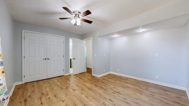 unfurnished bedroom with light wood-style flooring, baseboards, ceiling fan, and a closet