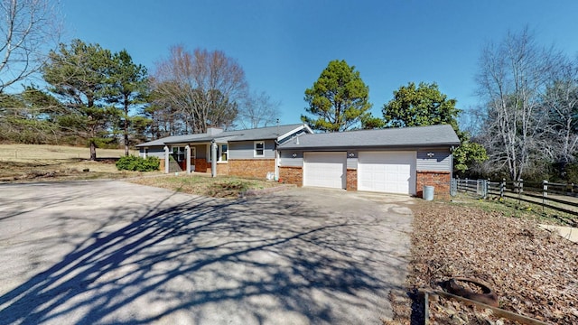 ranch-style home with a garage, brick siding, fence, driveway, and a chimney