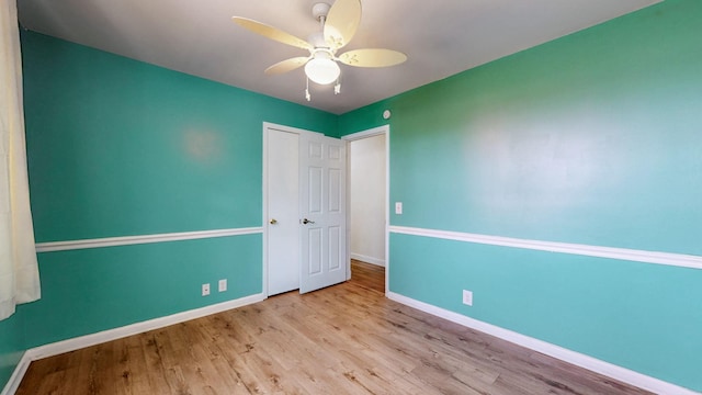 unfurnished bedroom with ceiling fan, wood finished floors, and baseboards