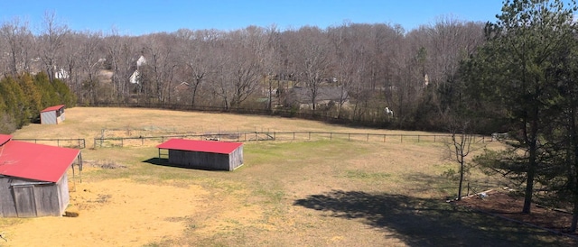 view of yard with an outbuilding, a rural view, fence, and a wooded view