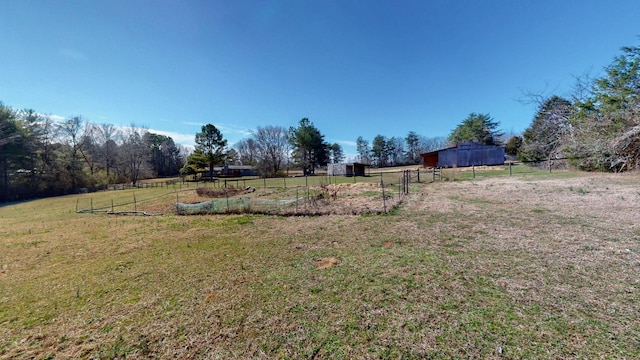 view of yard with an outbuilding, a rural view, and fence