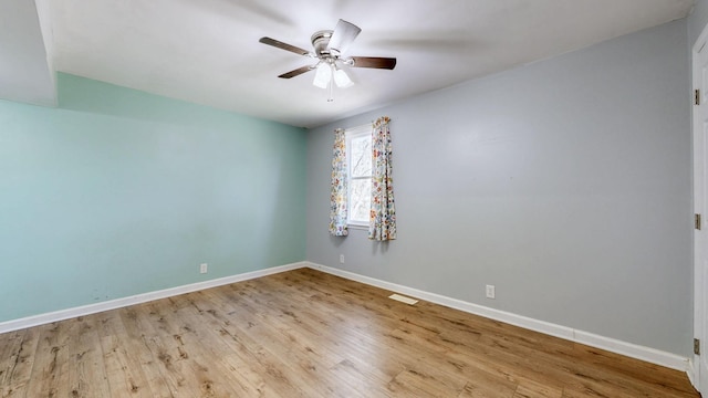 empty room with ceiling fan, wood finished floors, visible vents, and baseboards