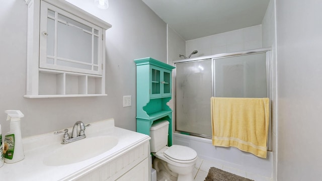 bathroom with toilet, combined bath / shower with glass door, vanity, and tile patterned floors