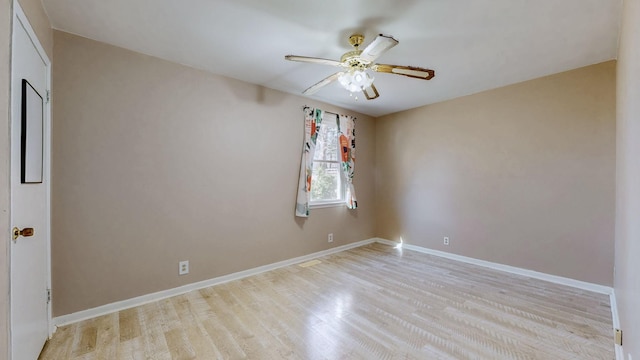 empty room featuring a ceiling fan, baseboards, and light wood finished floors