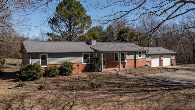 ranch-style house with a garage, driveway, a chimney, and brick siding