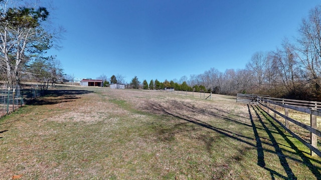 view of yard featuring a rural view, an outdoor structure, and fence