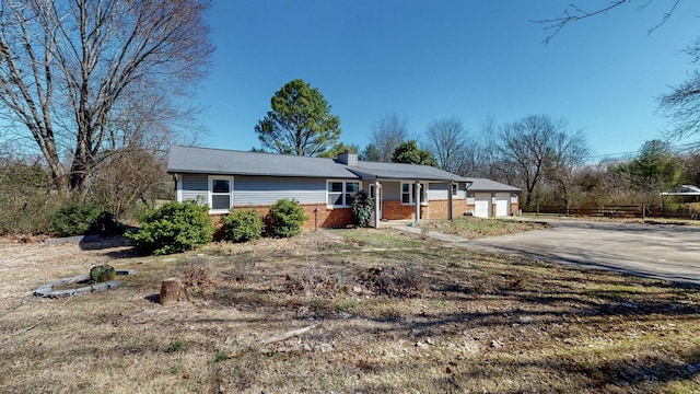 ranch-style home with a chimney and brick siding