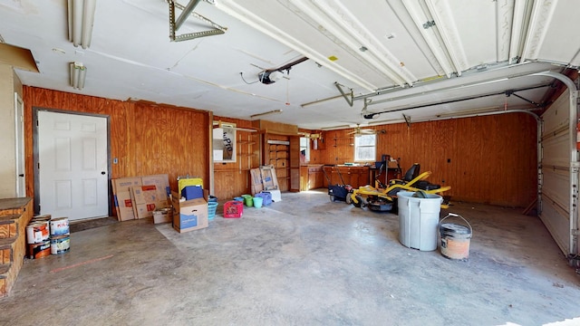 garage featuring a garage door opener and wooden walls