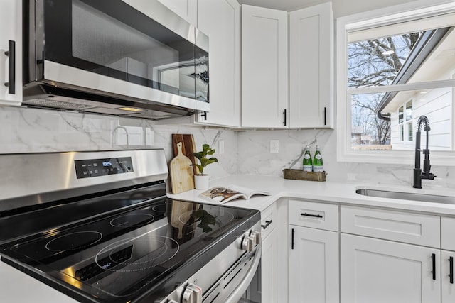 kitchen with backsplash, sink, white cabinets, and appliances with stainless steel finishes