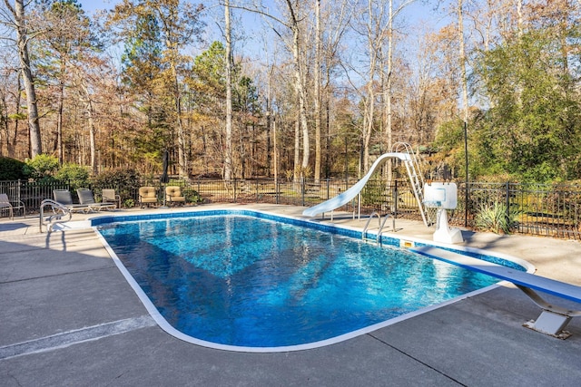 view of swimming pool featuring a diving board, a patio area, and a water slide